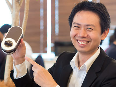 笑顔で端末を紹介している滝沢氏の写真