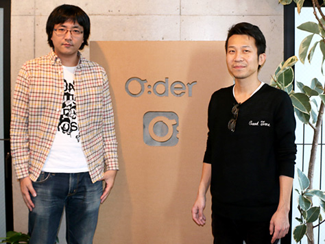 Oderロゴの前に立つ中野氏と石亀氏の写真